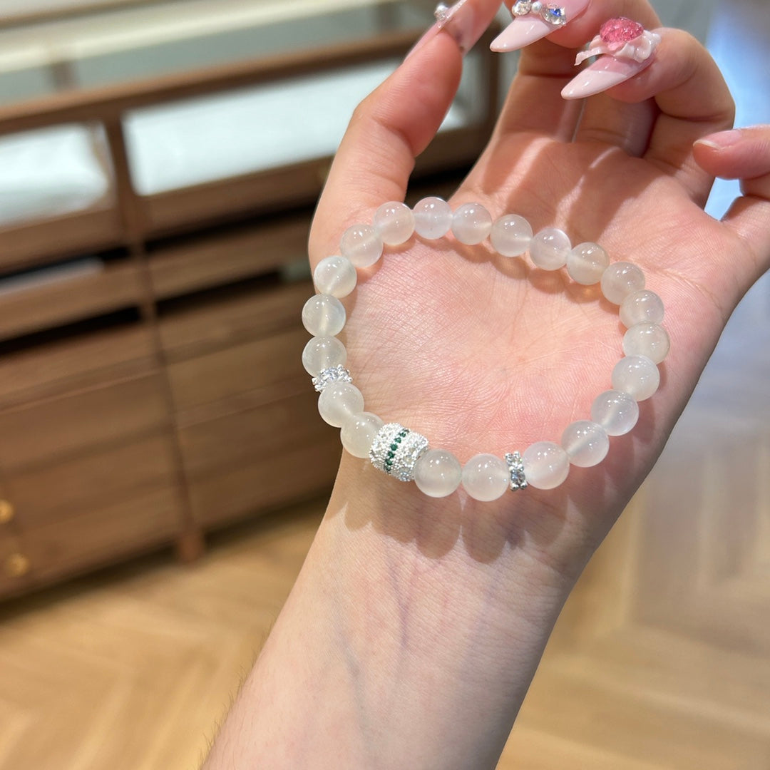 Hand holding a white moonstone bracelet with crystal accents – symbolizing purity, calm, and inner peace.