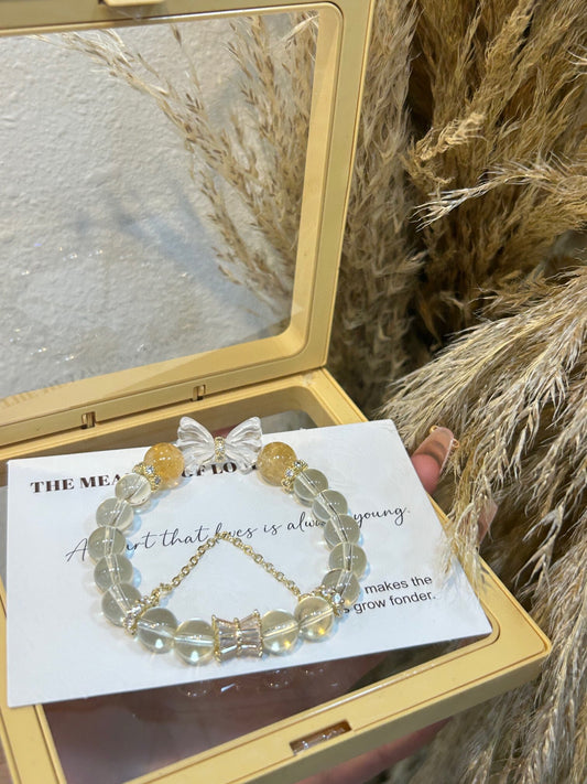 Hand holding lemon quartz and yellow azeztulite bracelet with white quartz butterfly charm – a stylish wealth and transformation crystal piece.